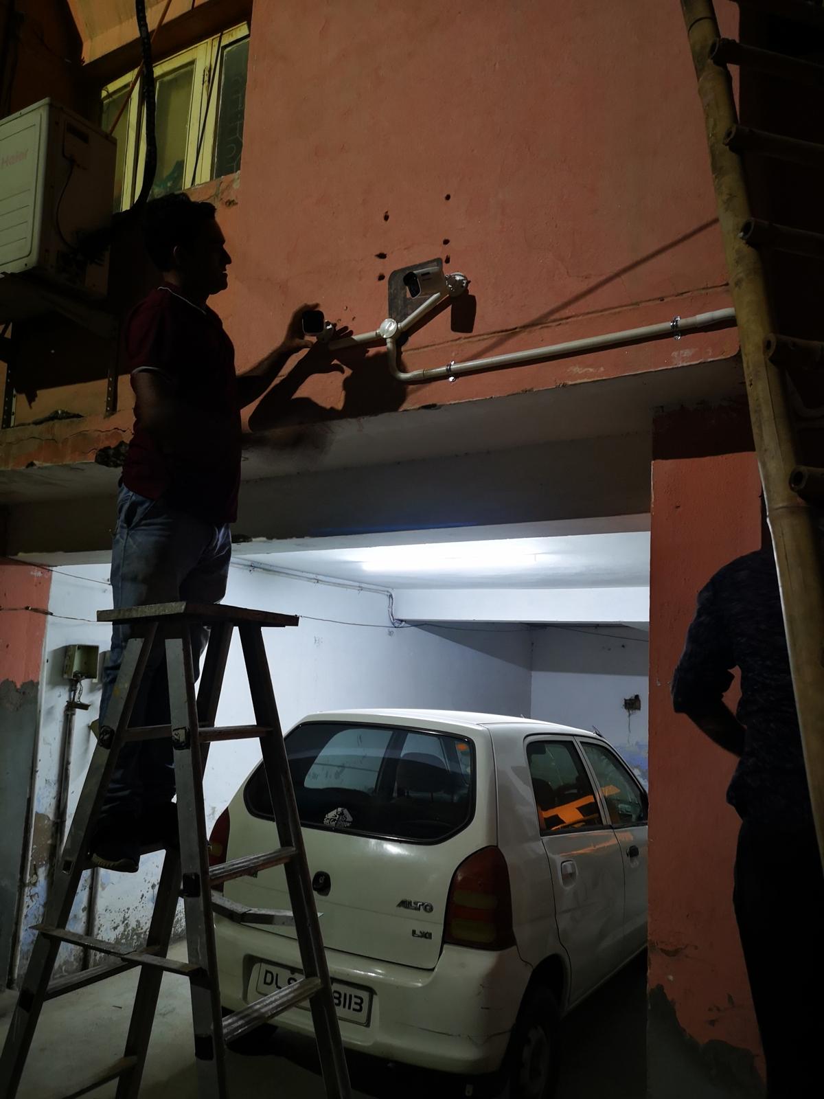 Technician aligning a CCTV camera on a mounting bracket over a parking entrance