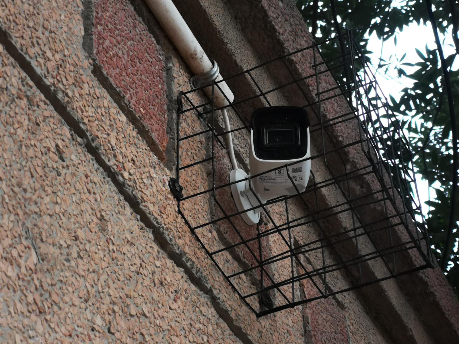 CCTV camera mounted inside a protective cage with conduit entry