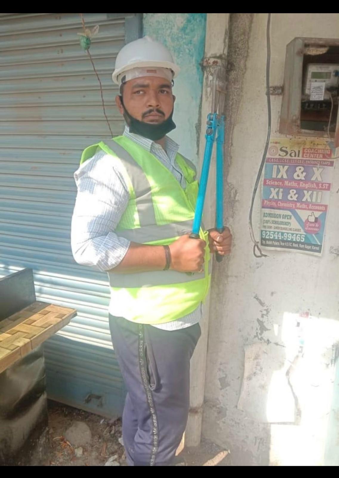 Technician holding a cutting tool beside a wall-mounted electricity meter box